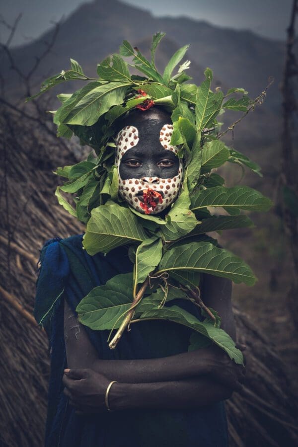 Photo of an African girl adorned with leaves and face paint.